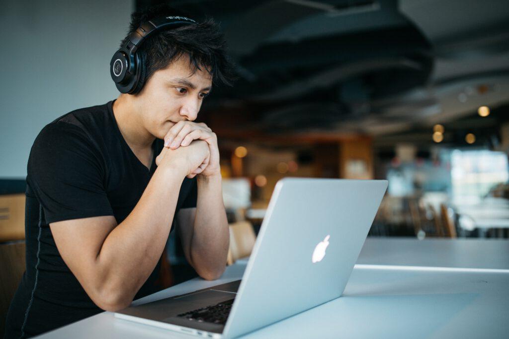 A man wearing headphones and looking at a laptop