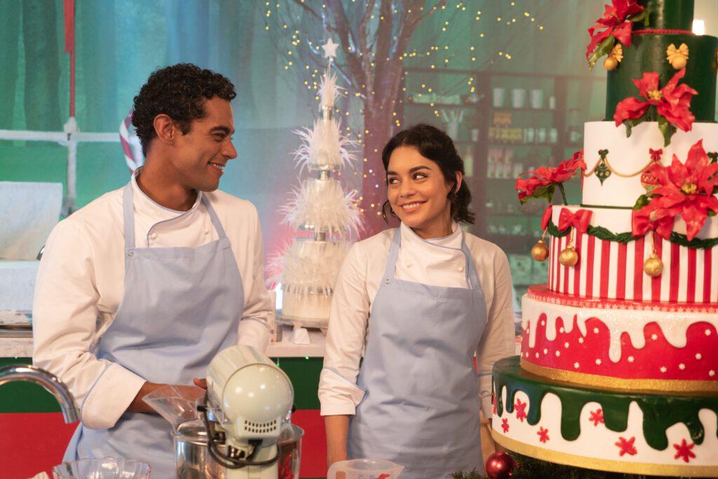 Two bakers smiling at each other with a Christmas cake next to them